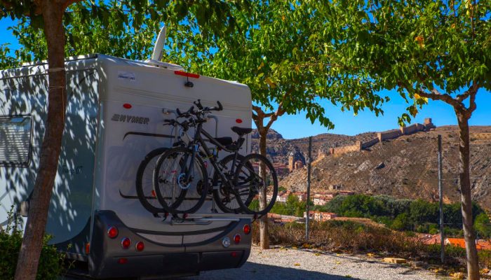 Autocaravana con bicicletas en parcela del Camping Albarracín con vistas al casco histórico de Albarracín.