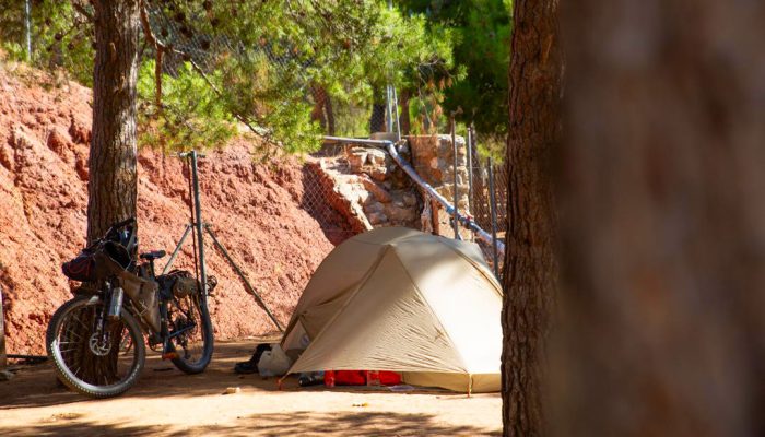 Tienda de campaña y bicicleta de cicloturismo en una zona de acampada bajo los pinos en el Camping Albarracín